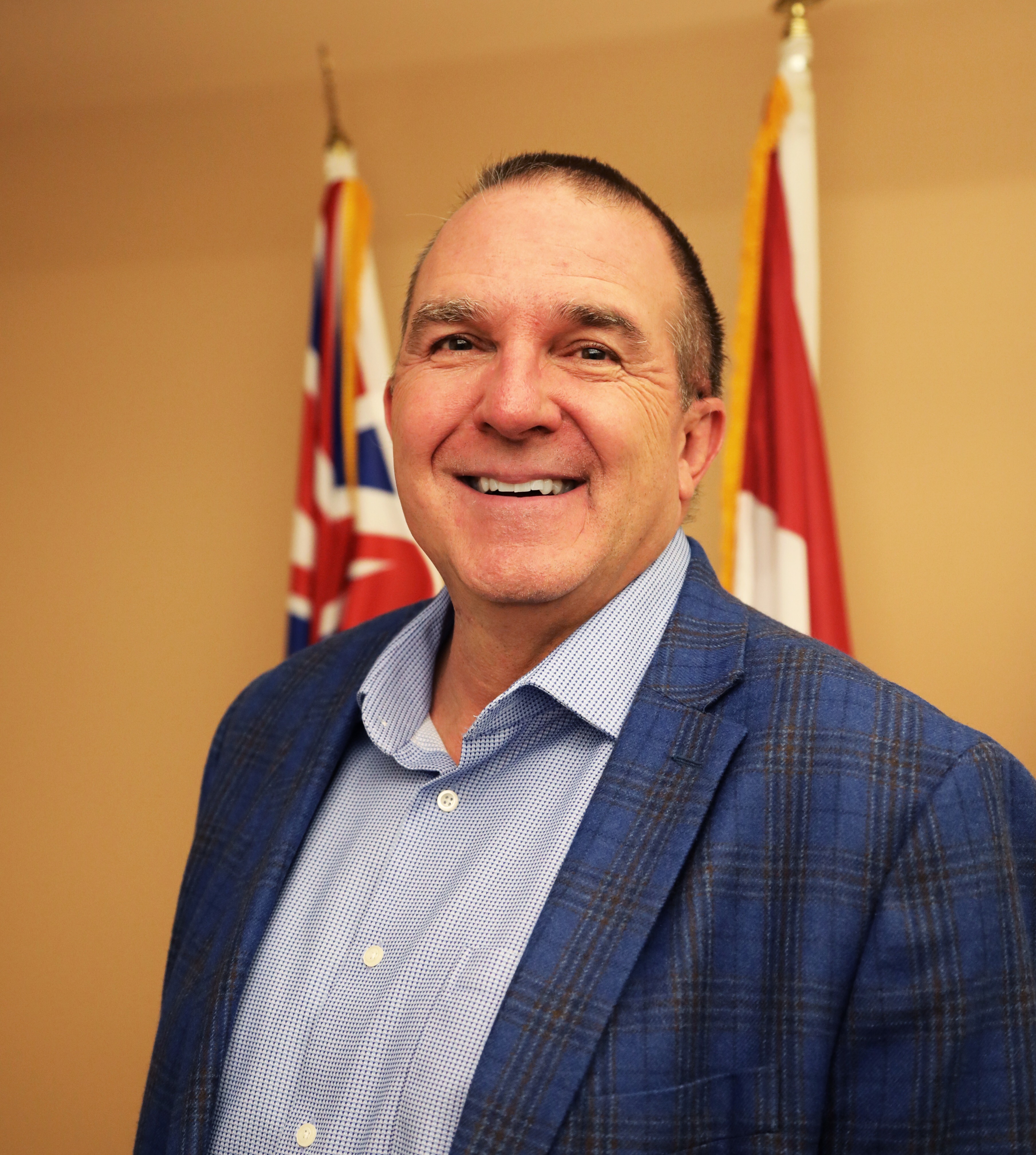 Paul Notman man in suit standing in front of flags and smiling
