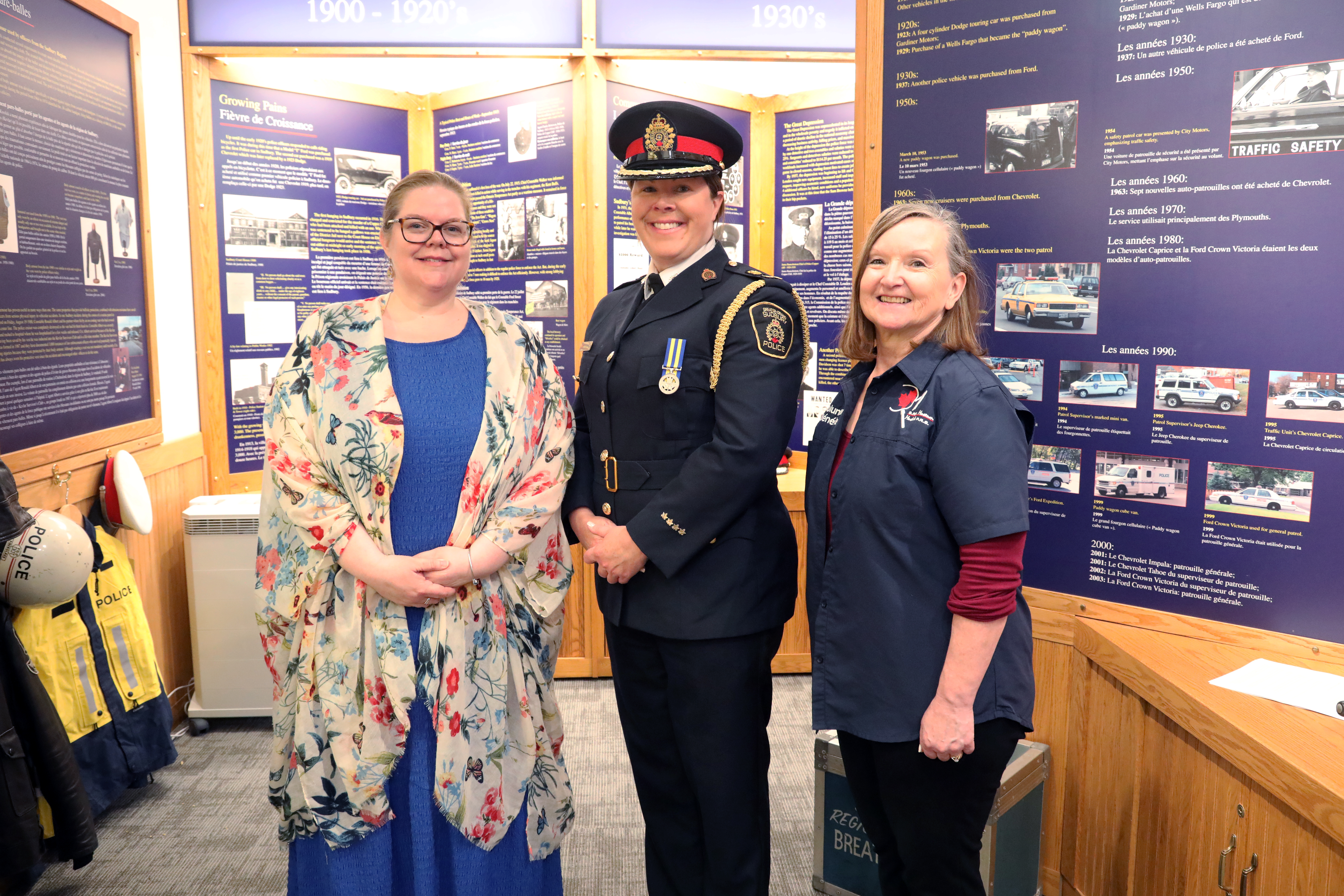 museum volunteers and the Deputy Chief of Police three women standing and smiling in a museum