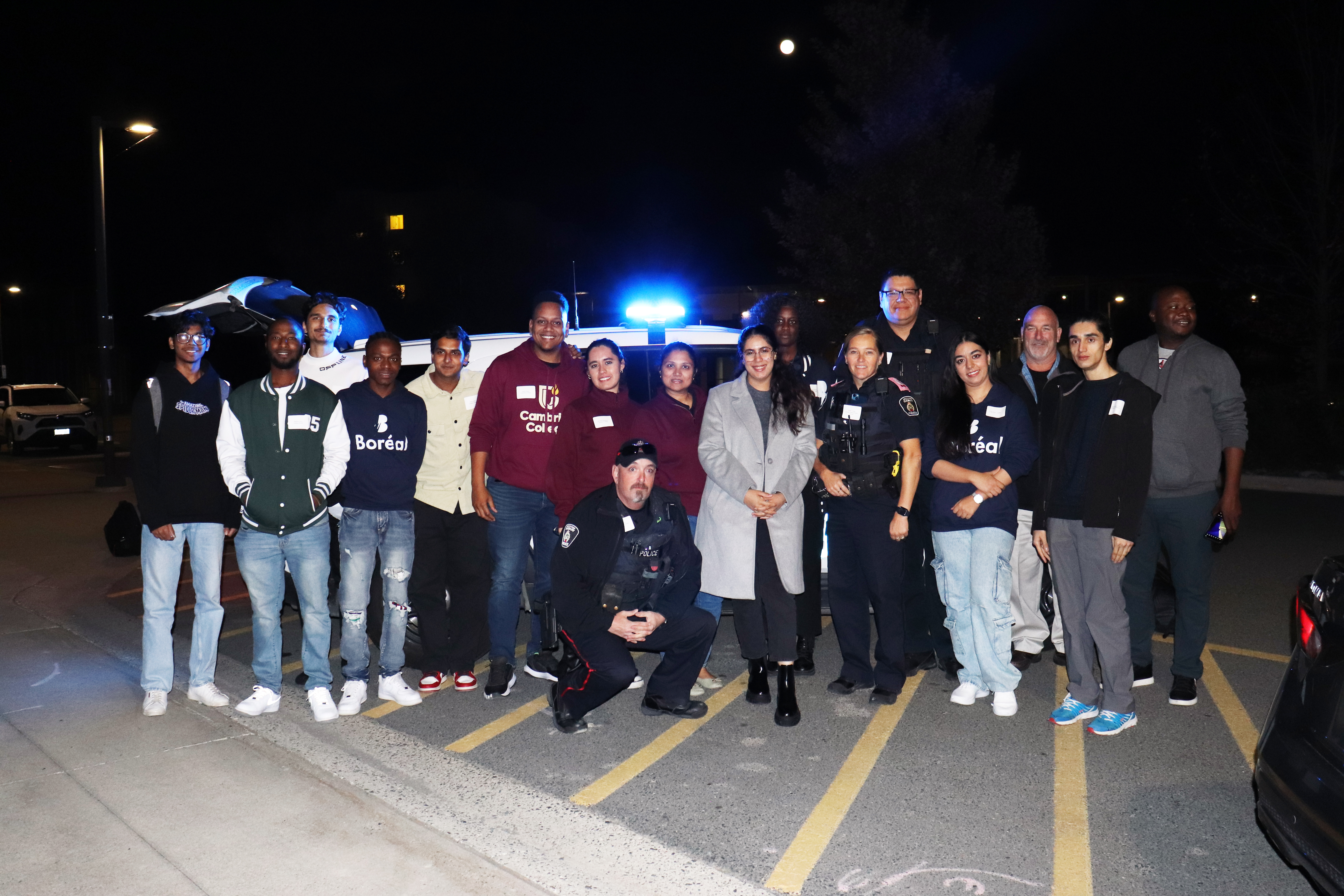Intercultural Ride Along participants group of people standing outside in front of a cruiser at night
