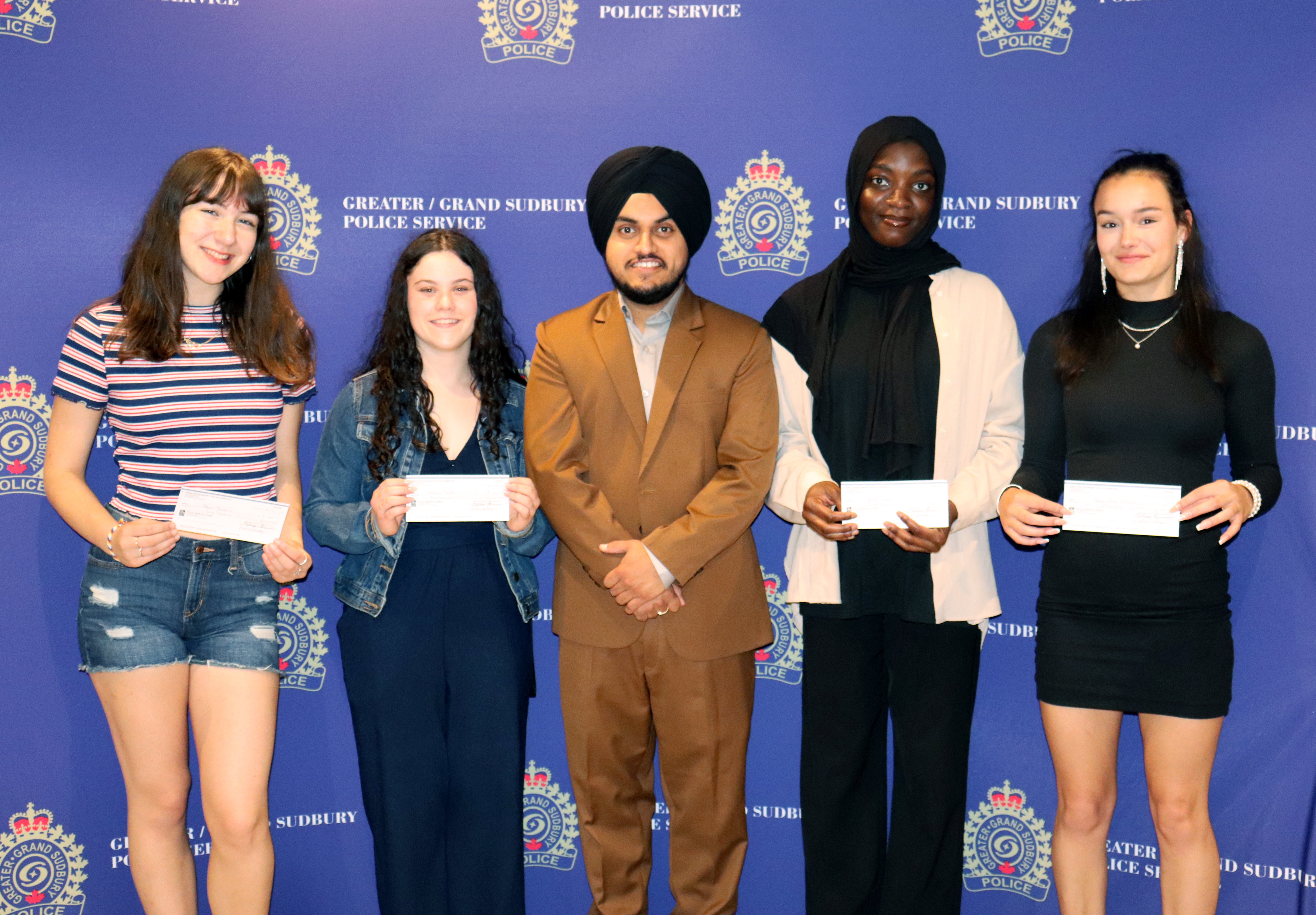 DAC bursary recipients group of people standing holding cheques
