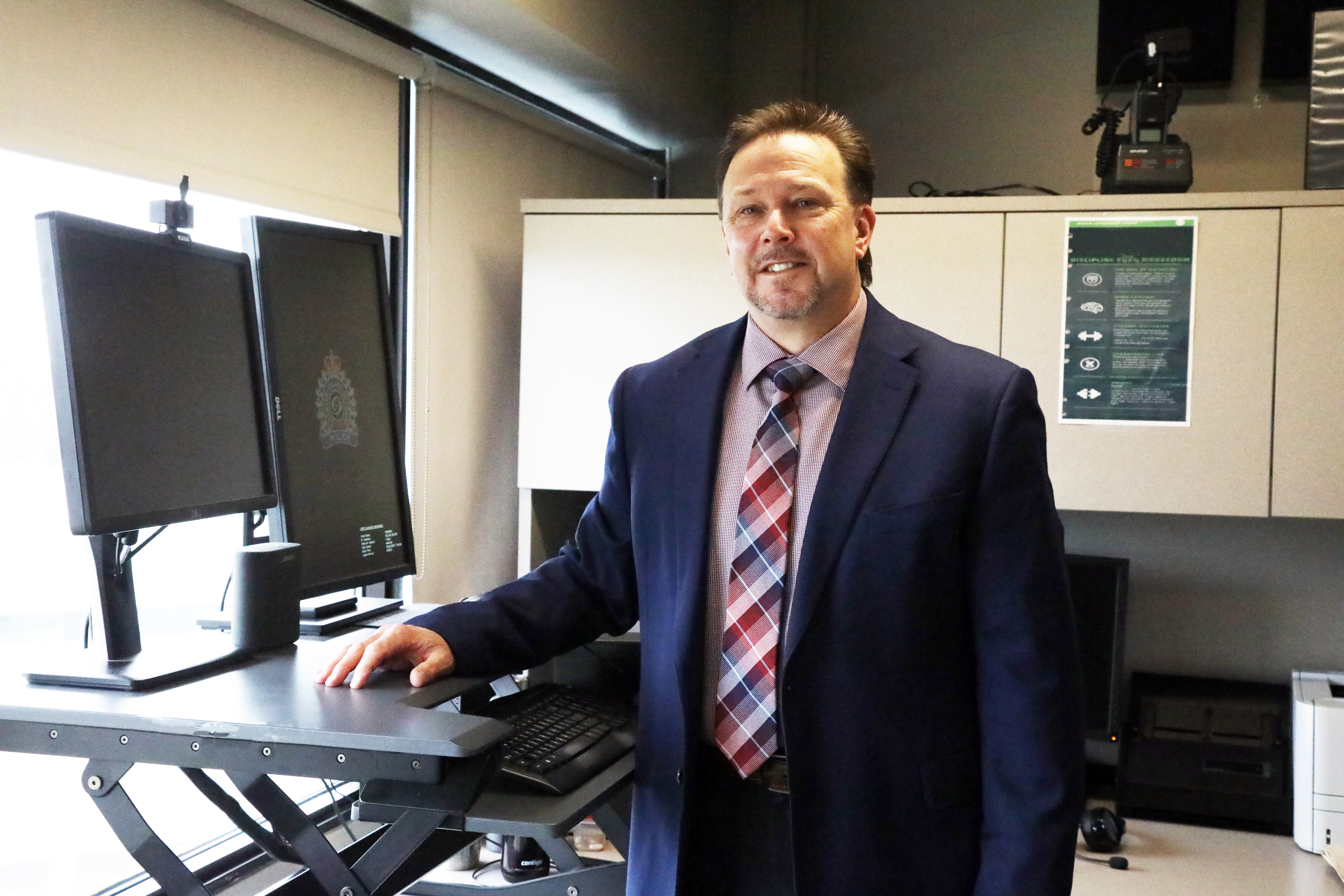 Craig Maki man in a suit standing beside computer