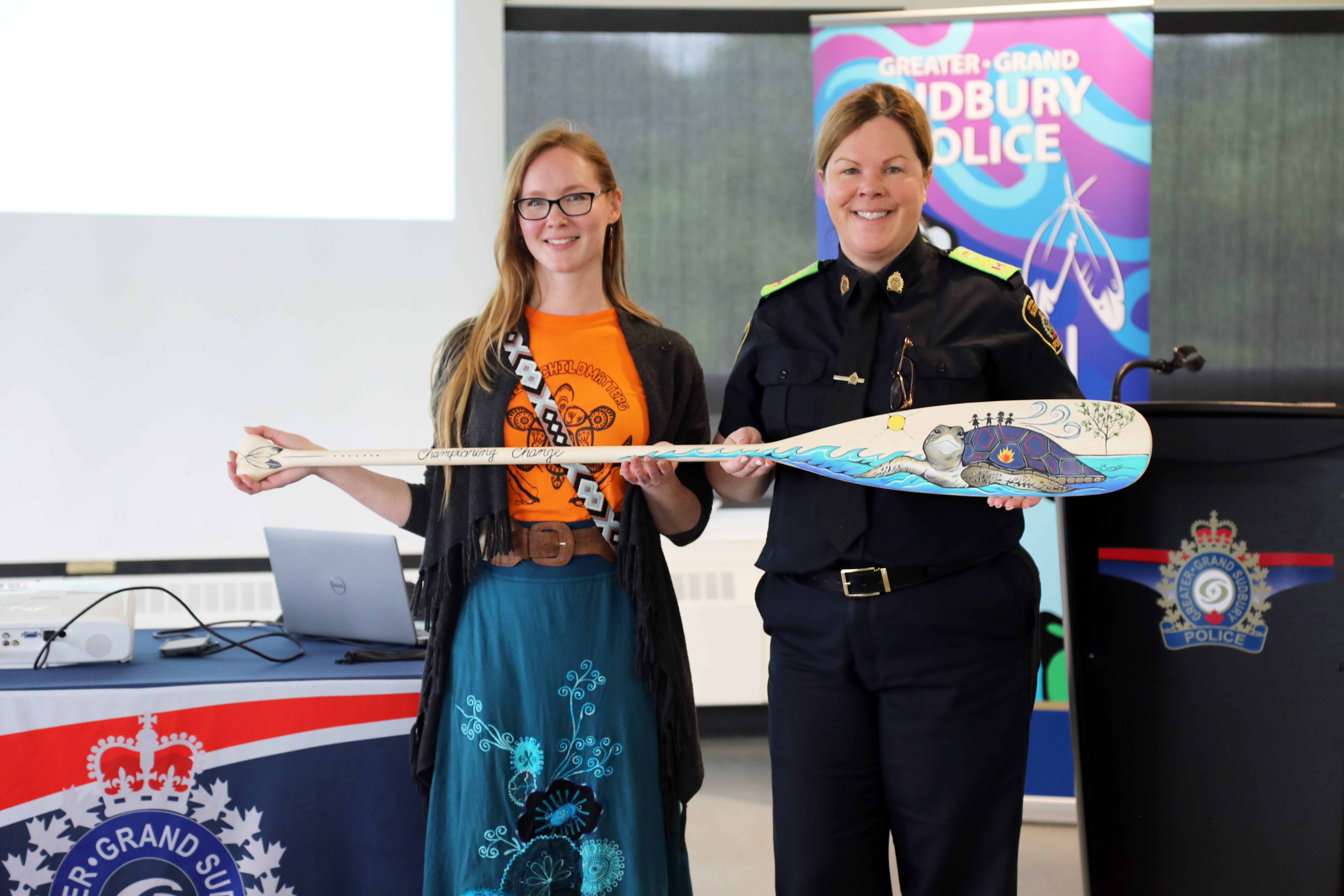 Championing Change paddle two women standing and smiling holding a paddle